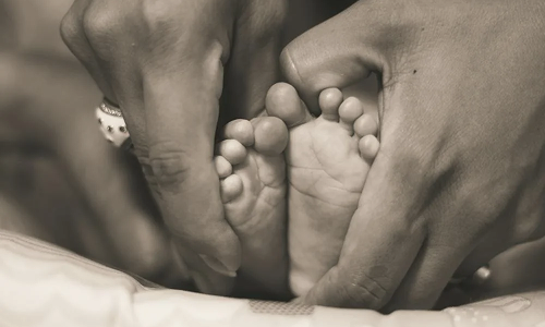 A infants feet being cradled by hands