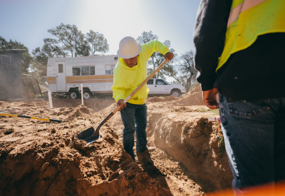 Worker using a shovel standing in a ditch