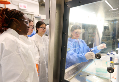 An instructor demonstrating lab equipment to a group of students