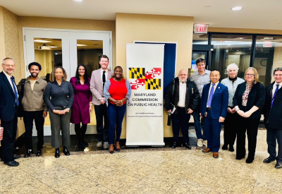 A group of people posing beside a banner for the Maryland Commission on Public Health