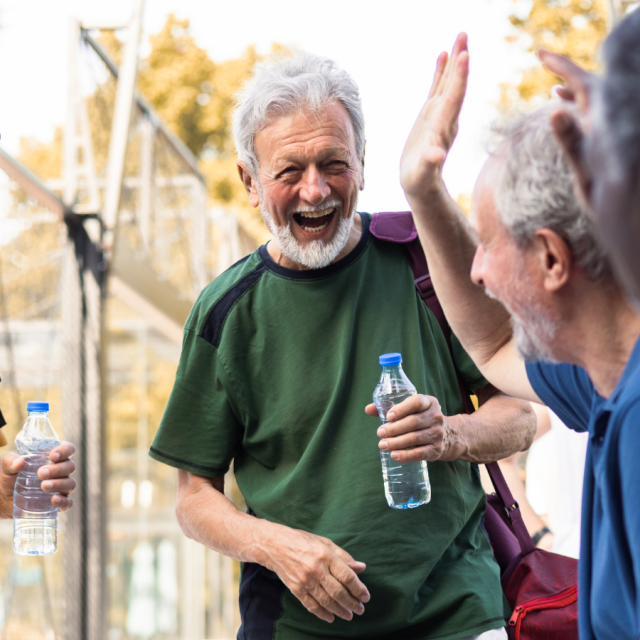 Happy senior friends greeting each other while meeting for a pickleball match