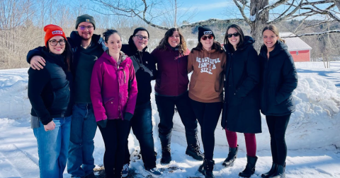 A group of eight young people pose for a group picture oustide in deep snow.