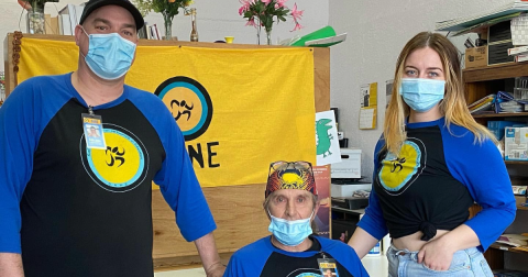 Three people pose in black and blue baseball tees with the SANE logo on them.