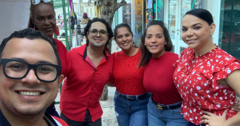 Six people all wearing red tops pose together for a picture.