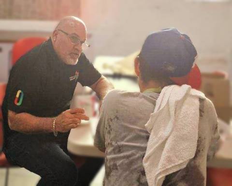 Peer navigator Robert Morales, in a black shirt, bald and bearded, advises a man in a gray tee and baseball cap.