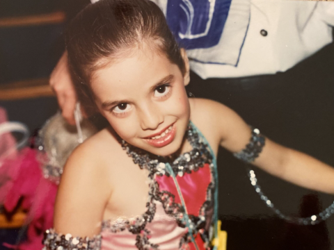 A young girl with brown hair, wearing a dance costume